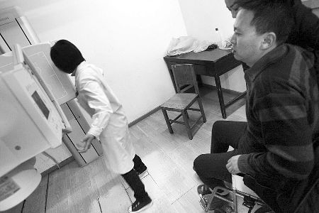 被打伤的李先生坐在轮椅上等待做腰部检查 